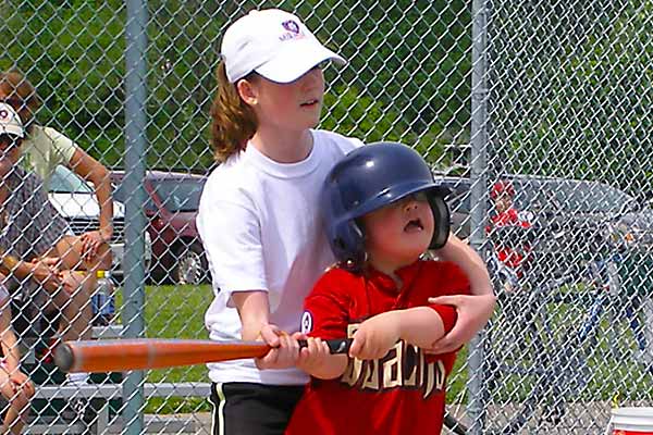 Batter swings with the help of a buddy